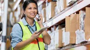 A person in a warehouse using their own tablet and phoen to complete inventory