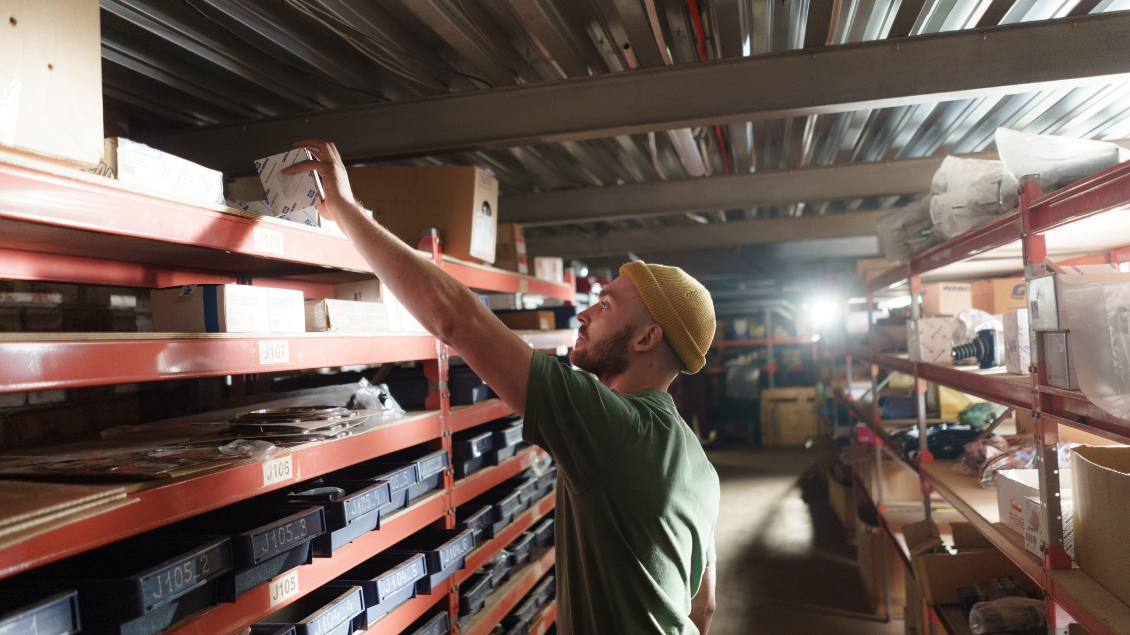  warehouse setting with man looking at an item on a shelf 